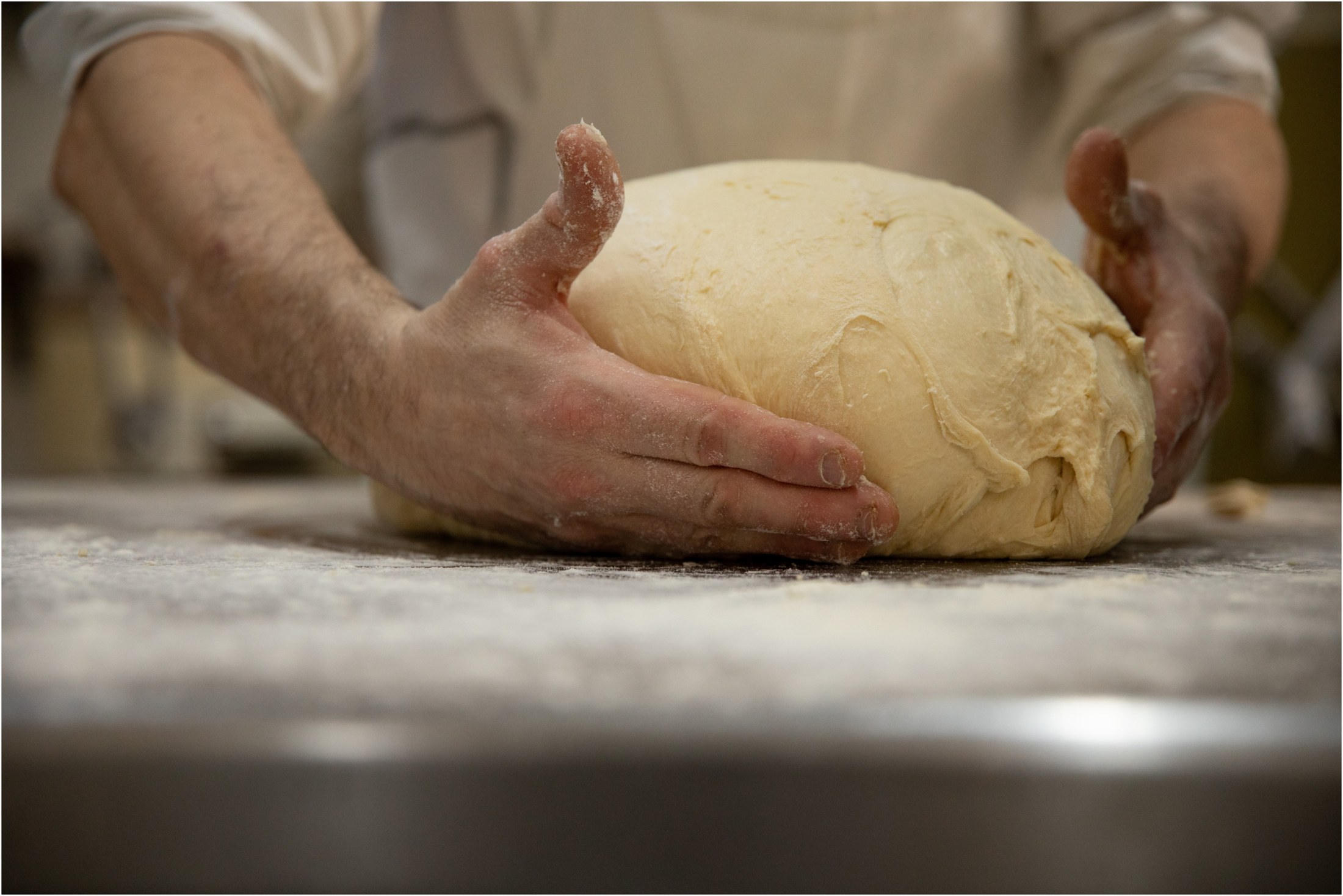 Pasticciere che lavora a mano un impasto sul banco del laboratorio a Nuoro