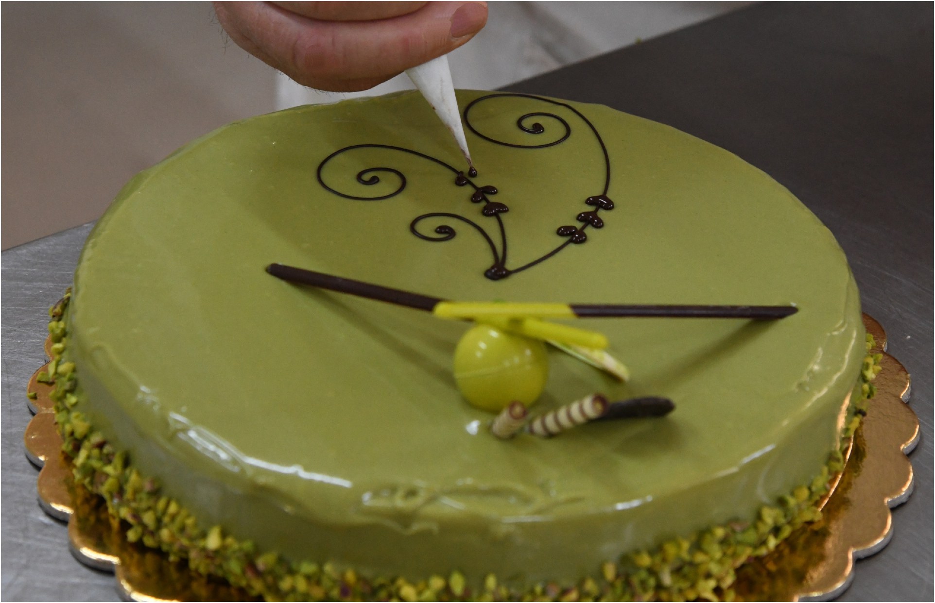 Torta glassata al pistacchio rifinita a mano nel laboratorio di pasticceria a Nuoro